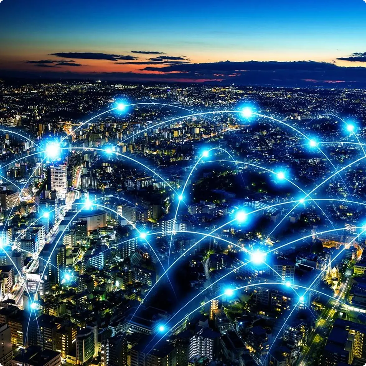 Aerial view of a city at dusk with bright blue network lines and glowing points connecting various locations, representing digital connectivity.